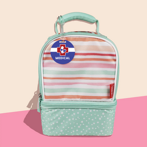 InchBug allergy alert bag tag with a medical icon, displayed on a green and white bag handle, placed against a two-toned beige and pink background