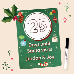 A personalized Christmas countdown board with a green background, featuring illustrations of Gingerbread, hot chocolate drink, and other Christmas items. The board has a white circle with 25 written on it in black ink, and below it is white text that reads 'Days until Santa visits Jordan & Joy'.