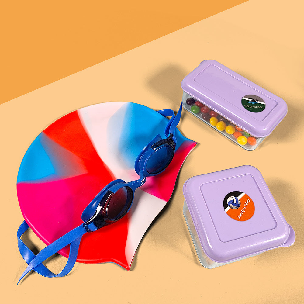 InchBug Circle Name Labels - Sports on food containers beside a swimming cap and googles