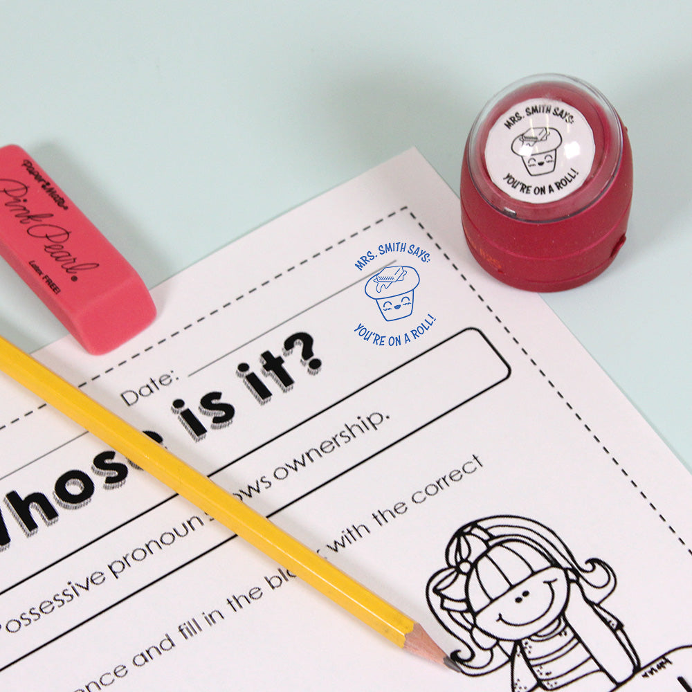 Dark red personalized teacher stamp with self-inking base, with a unique design featuring a teacher's name and a phrase 'You're on a roll!'.