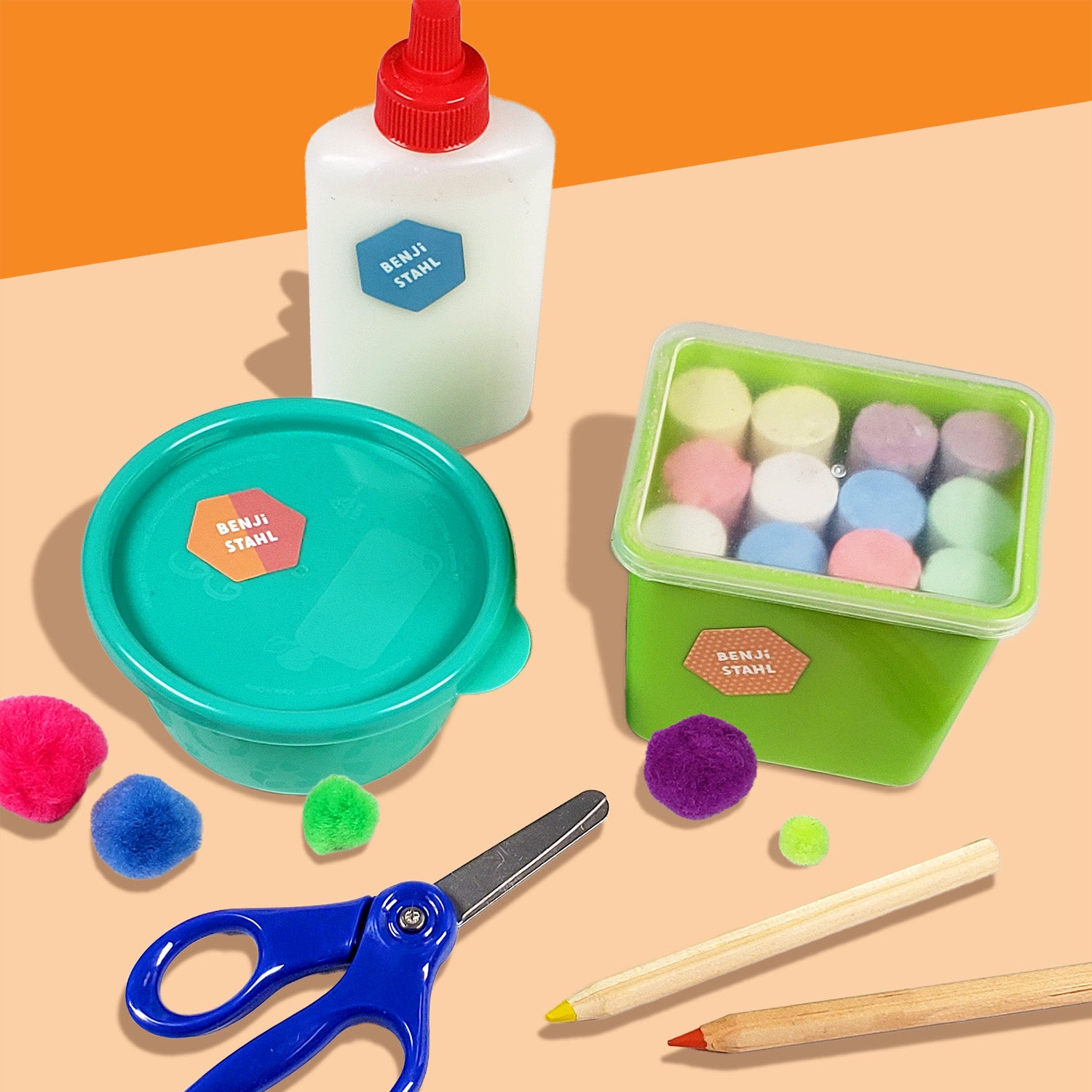 A variety of colorful InchBug hexagon sticky name tags displayed on different surfaces with a pair of scissors, colored pencils, and various children's items such as a green container and pom-poms.