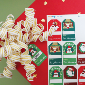 red wrapper with star designs and white and gold ribbons placed alongside InchBug personalized holiday gift tags