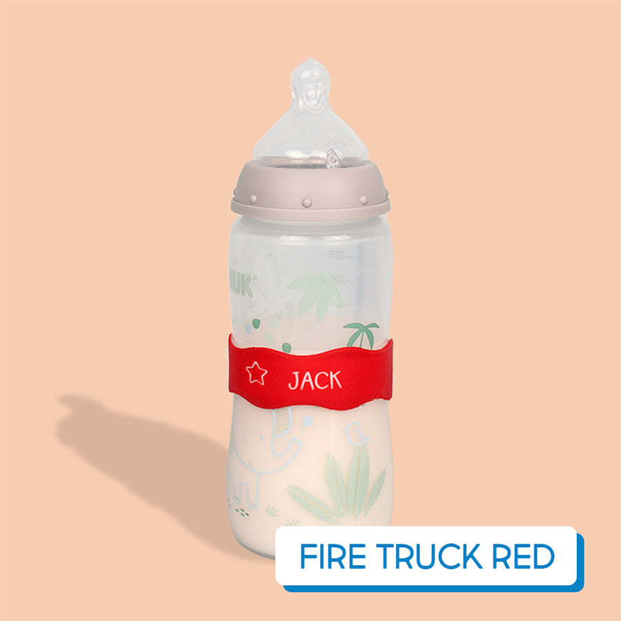 Baby bottle with red InchBug Orbit Label on a beige background, labeled 'Fire Truck Red'.