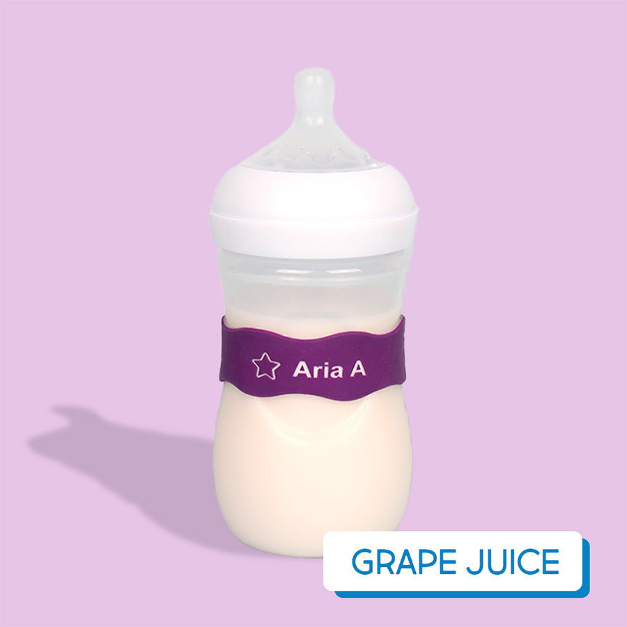 Baby bottle with purple InchBug Orbit Label on a pink background, labeled 'Grape Juice'.