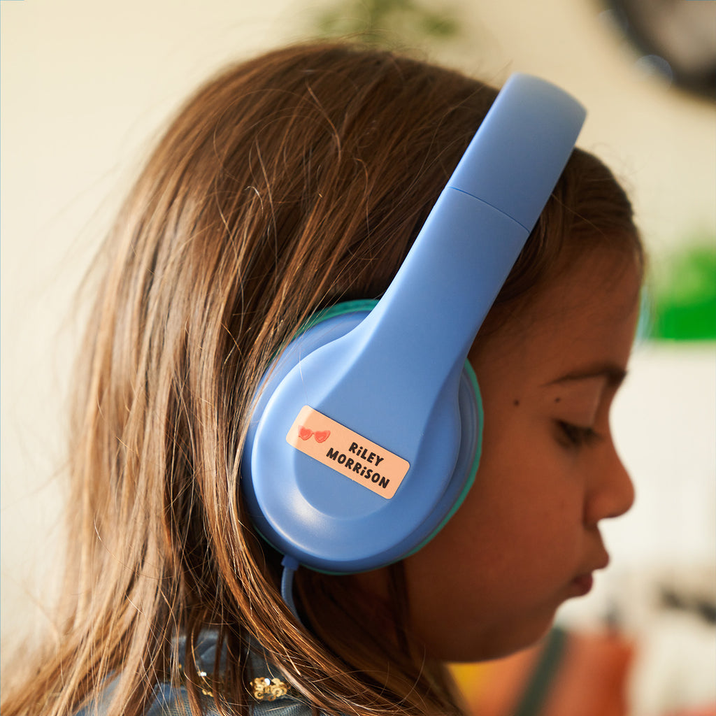 kid wearing a light blue headphone labeled with an InchBug sticker name label