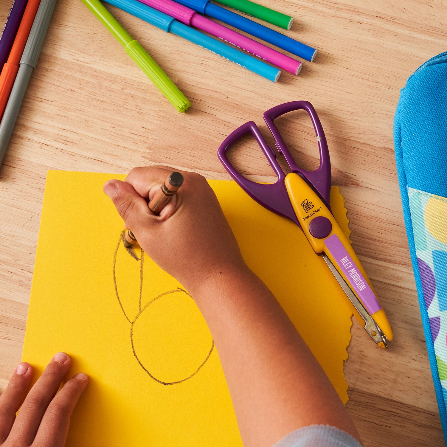kid doodling on a yellow paper using a brown crayon