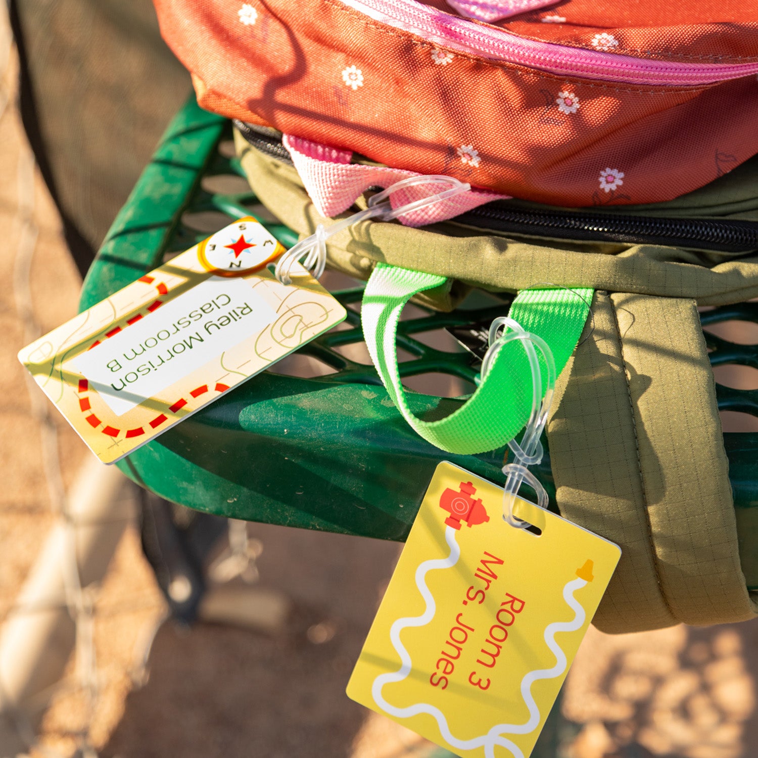 2 backpacks stacked on top of each other, both with rectangular InchBug school bag tags