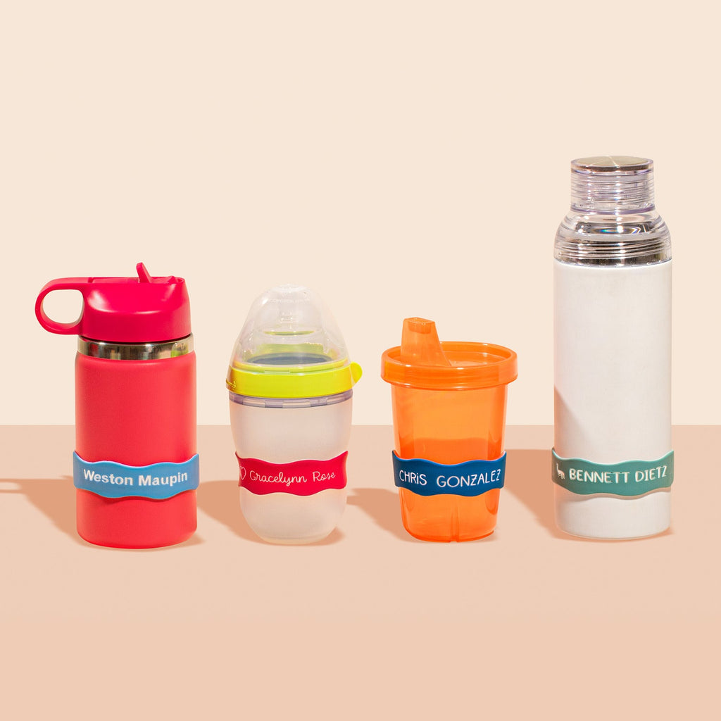 A collection of baby bottles and food containers with colorful personalized 
InchBug Orbit Labels® Personalized Water Bottle Labels, showcasing a variety of colors and labels, some with caps and some with handles.