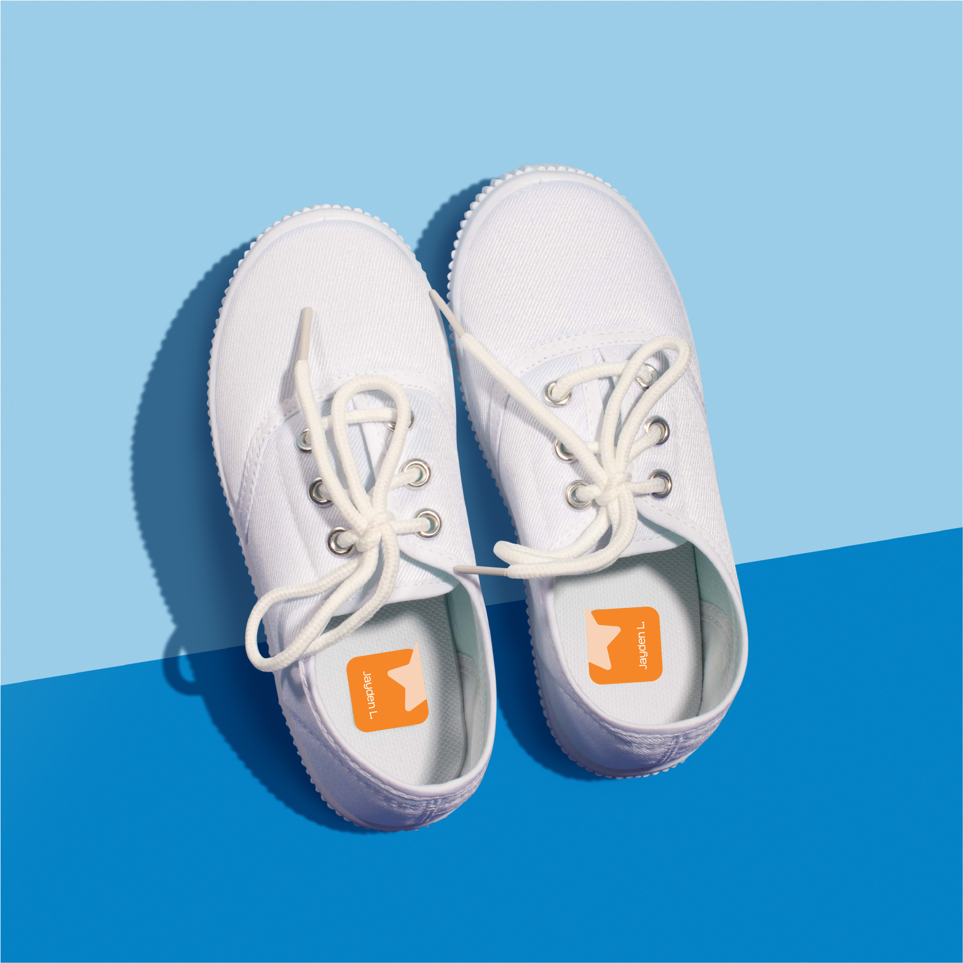 A pair of white shoes with a single orange InchBug ShoePal label attached to one side, displayed against a blue background.