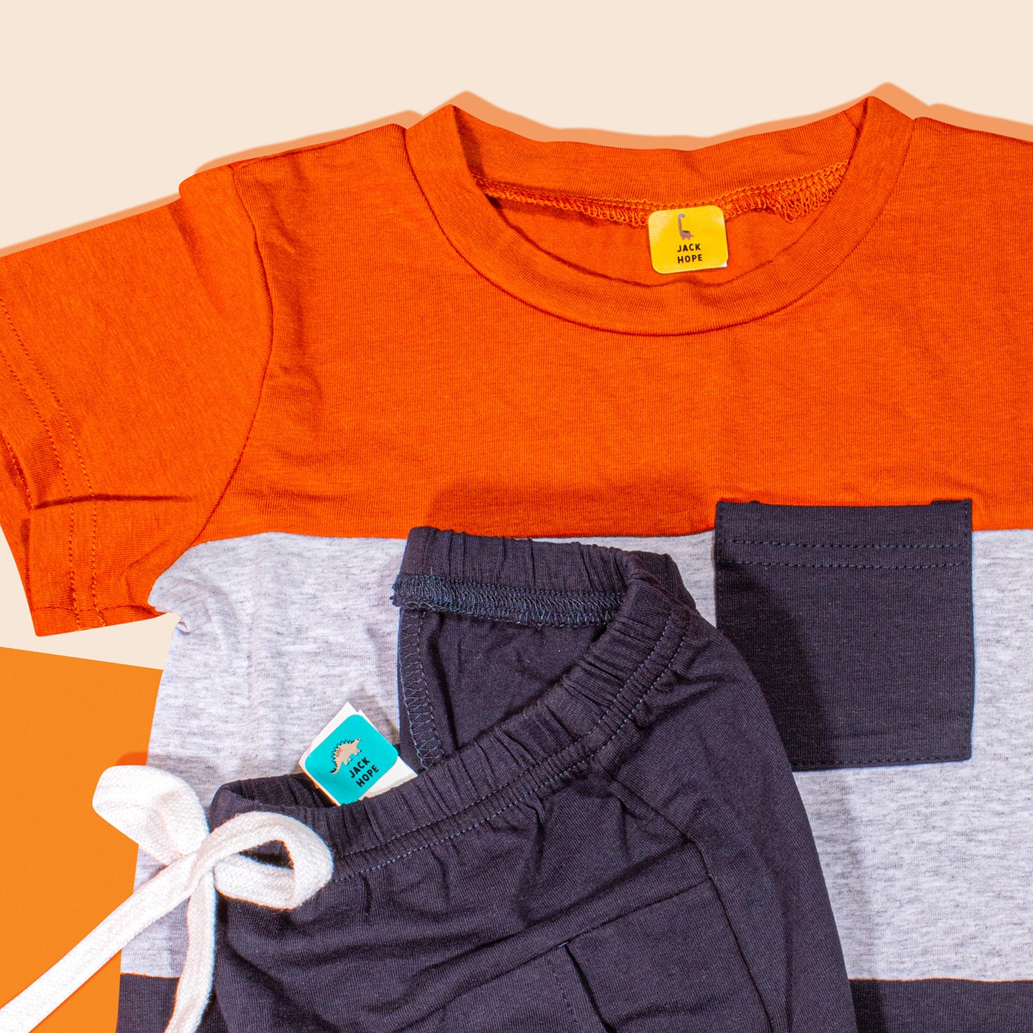 A set of orange and gray kids' clothing each with visible yellow and blue InchBug TagPal Kids Clothing Labels 