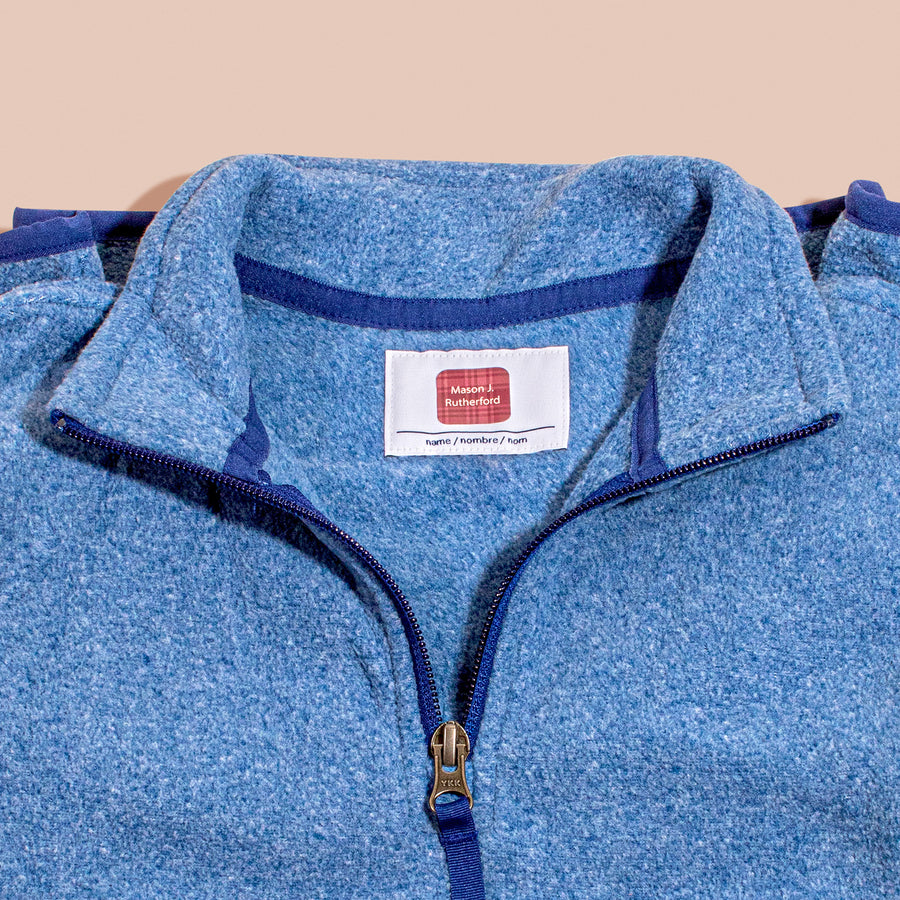 A close-up of a blue garment with an InchBug TagPal Kids clothing label tag