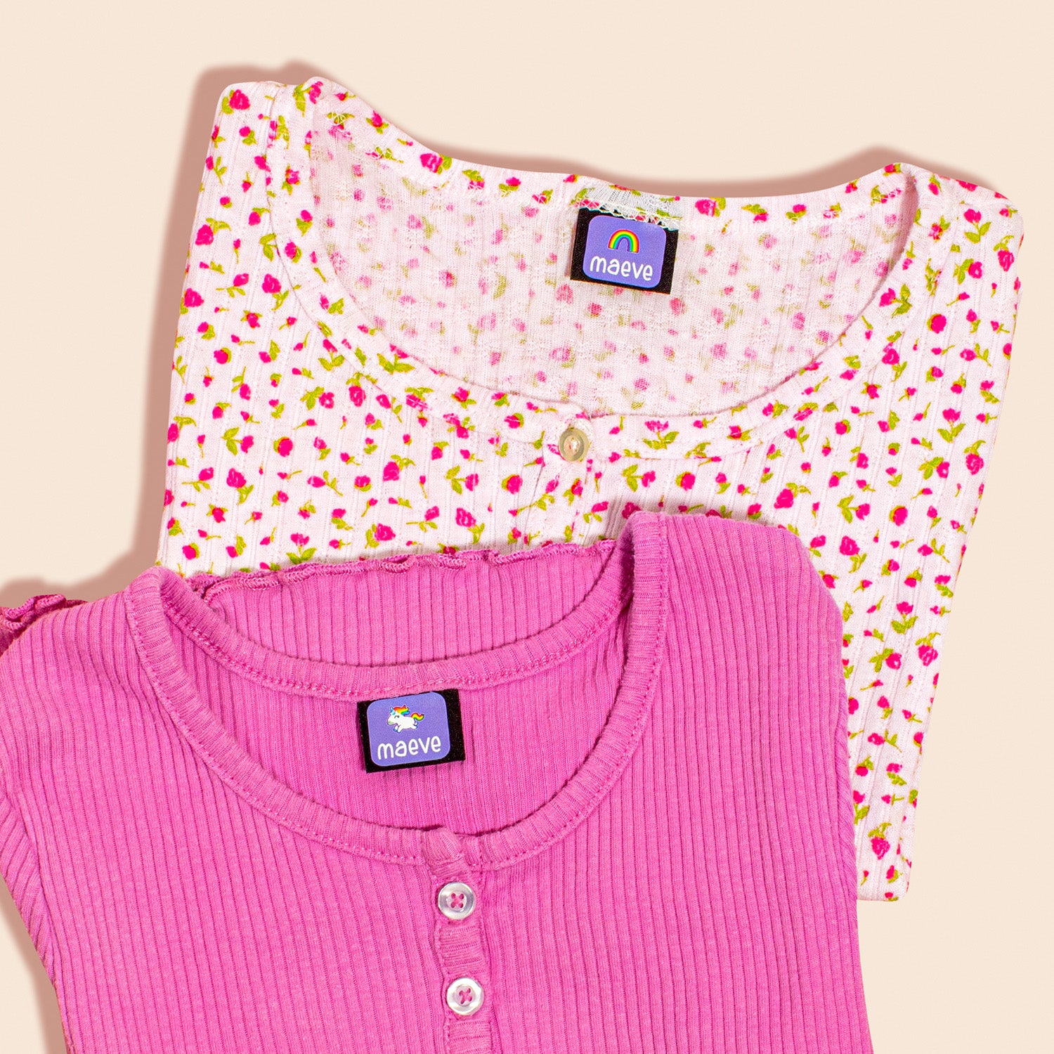 Two children's clothing items, one with a floral pattern and the other in a solid pink color, each with InchBug TagPal Kids Clothing Labels attached to the care tag.