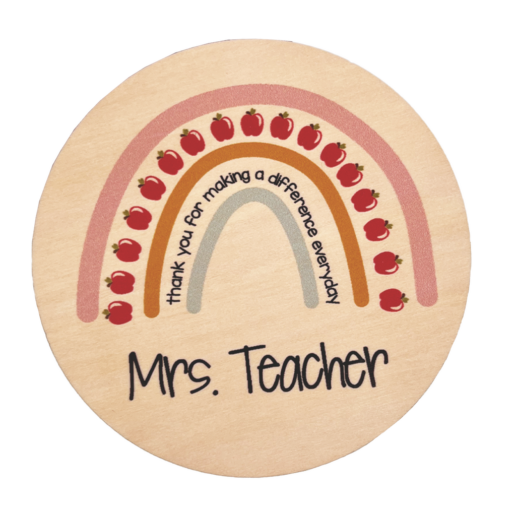 A round plywood coaster with a personalized message that reads 'Mrs. Teach' surrounded by colorful pencil graphics.