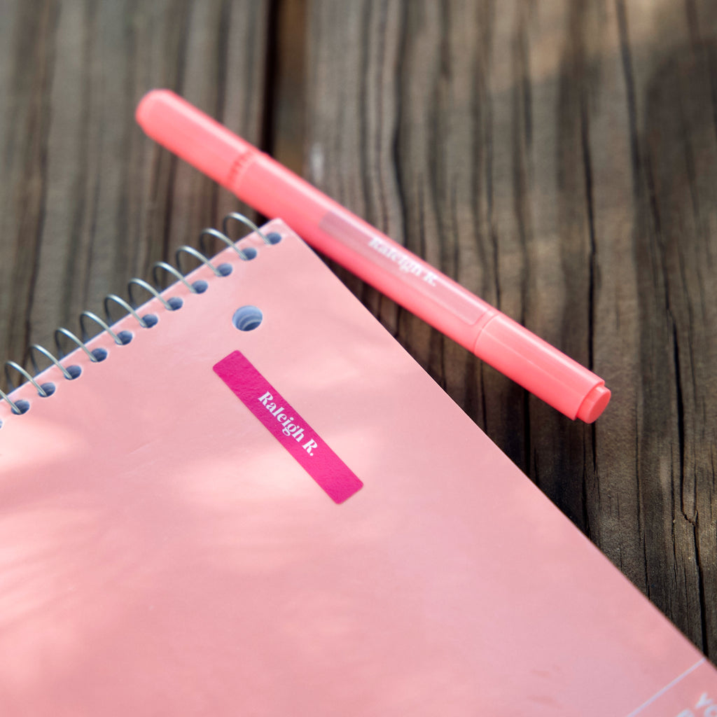 pink notebook and pink pen labeled with InchBug mini name stickers for kids