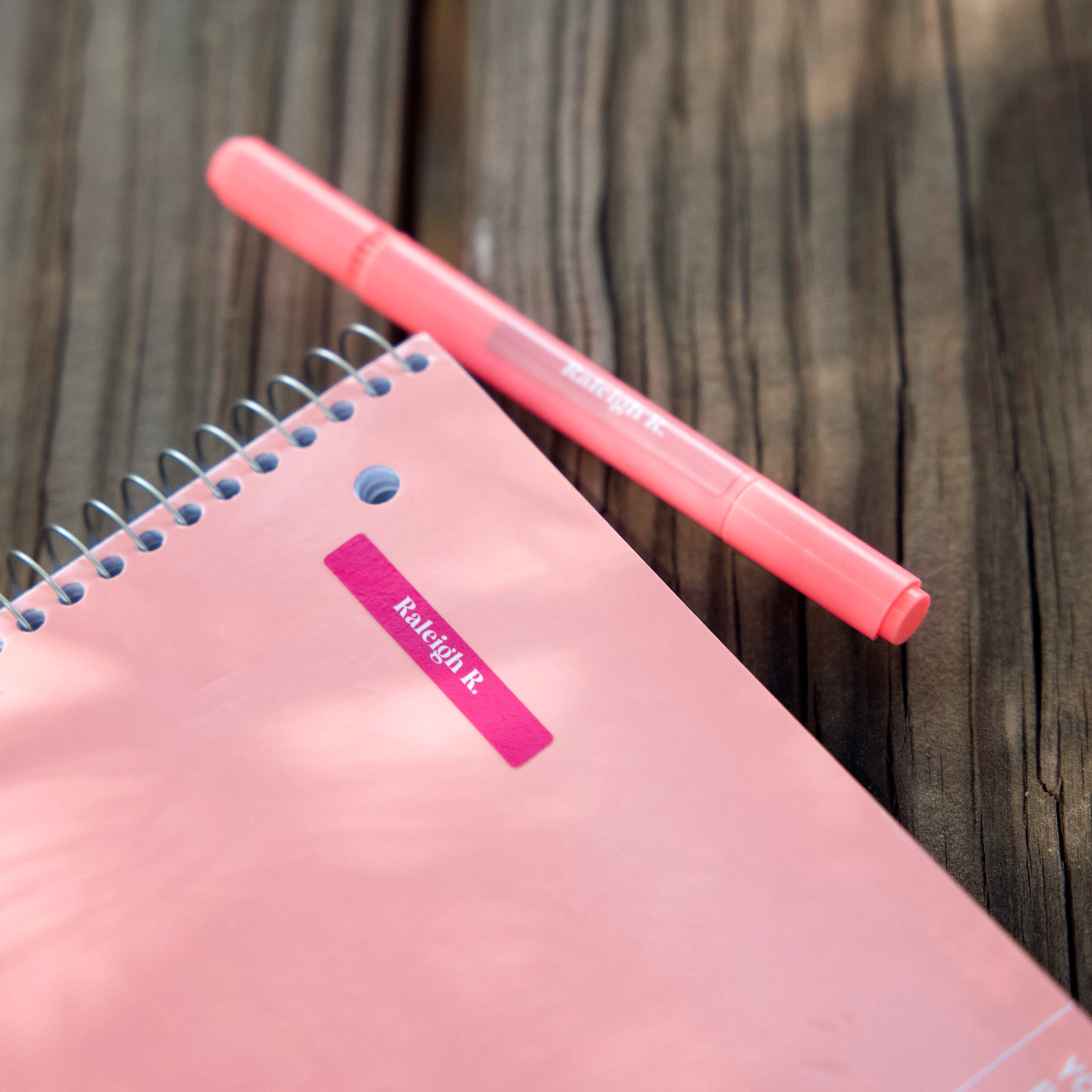 pink notebook and pink pen labeled with InchBug mini name stickers for kids