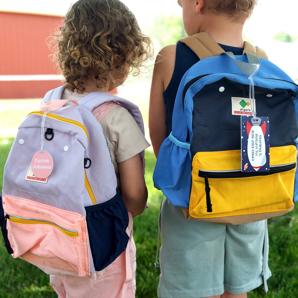 2 kids with backpacks, one with InchBug circular bag tag, the other with rectangle bag tag
