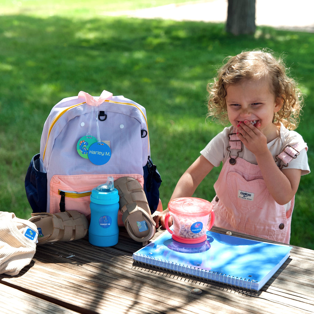 happy kid with her InchBug-labeled items on the table