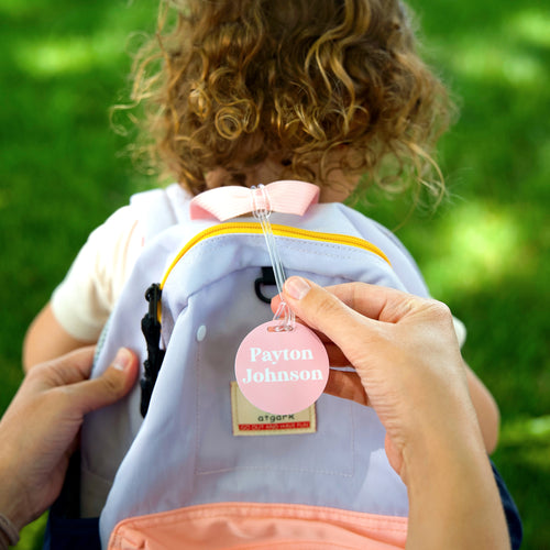 A close-up view of InchBug's personalized preschool name tag for bags, while the parent is holding it.