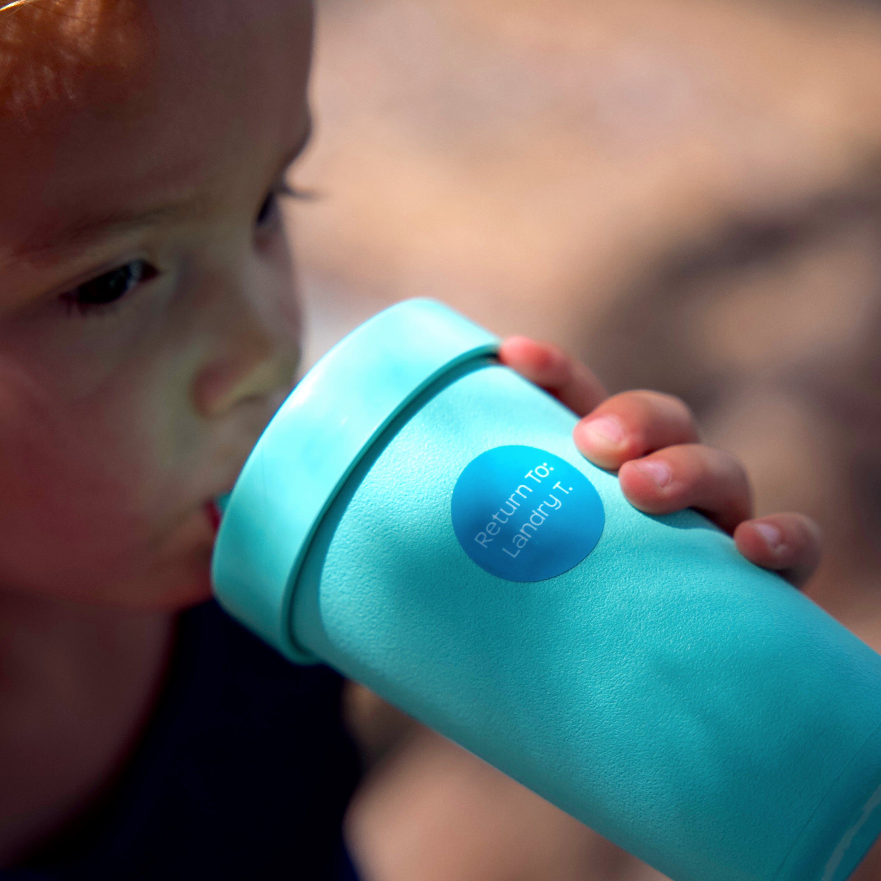 kid drinking from a blue-green sippy cup labeled with a blue InchBug name label sticker