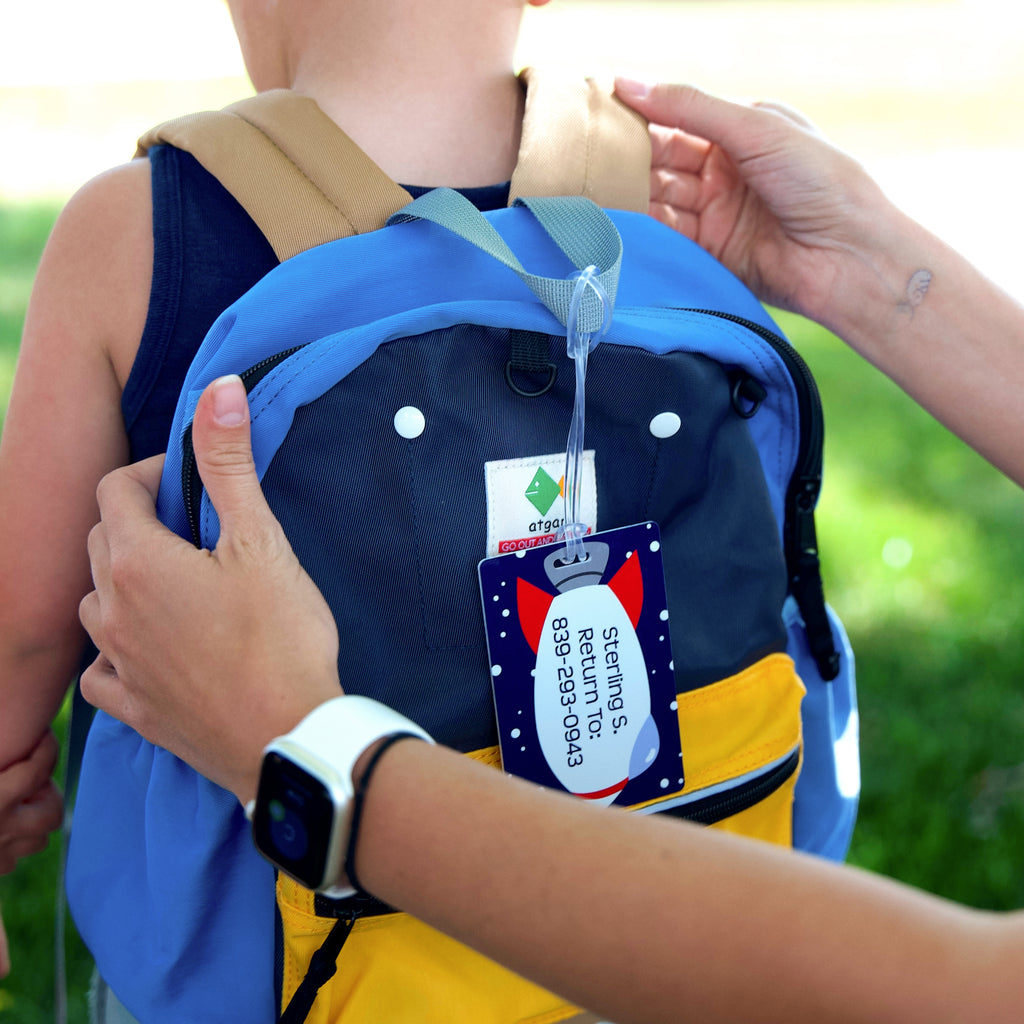 person fixing the kid's bag with hanging InchBug Rectangle Bag Tag