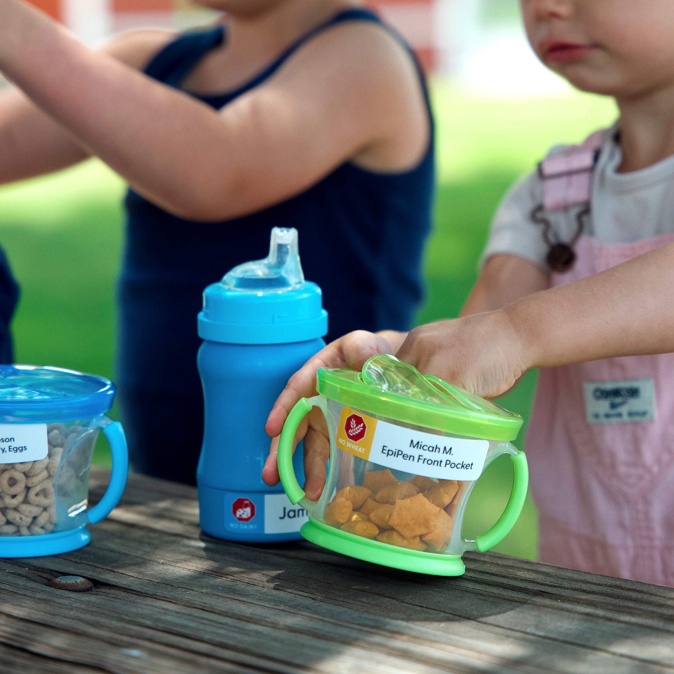 kid getting a snack from a food container labeled with InchBug allergy alert name sticker for kids