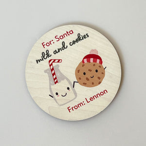 InchBug's round, personalized coaster with 'Milk and Cookies' text and illustrations of a milk bottle, cookies, and a Santa hat.