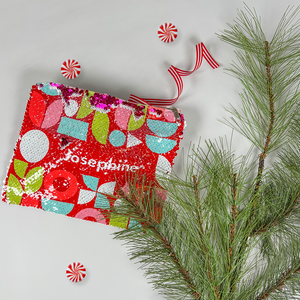 red InchBug personalized sequin pouch designed with various shapes, alongside a pine tree branch