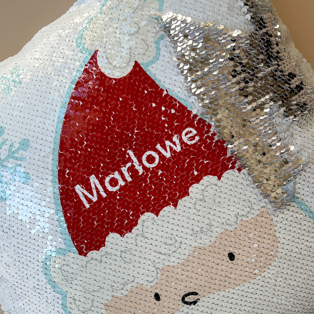 close-up view of the sequined InchBug Silly Santa pillow, the silver side is seen