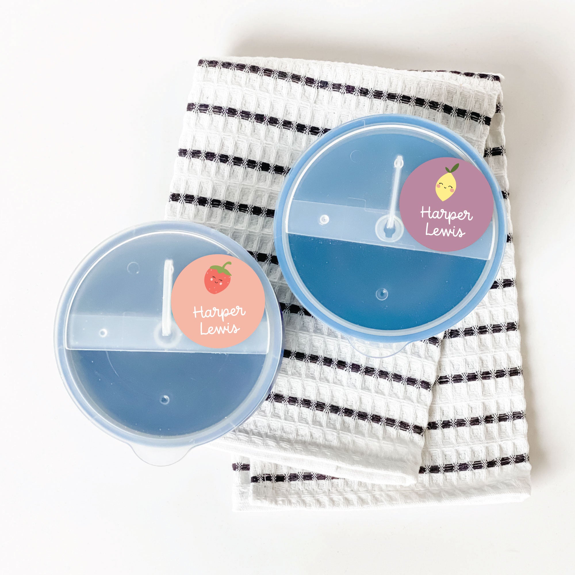 top view of 2 blue food containers, their lids labeled with circular InchBug name sticker tags