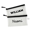 Two black InchBug personalized zipper pouches with the names 'WILLIAM' and 'Naomi' printed on them.