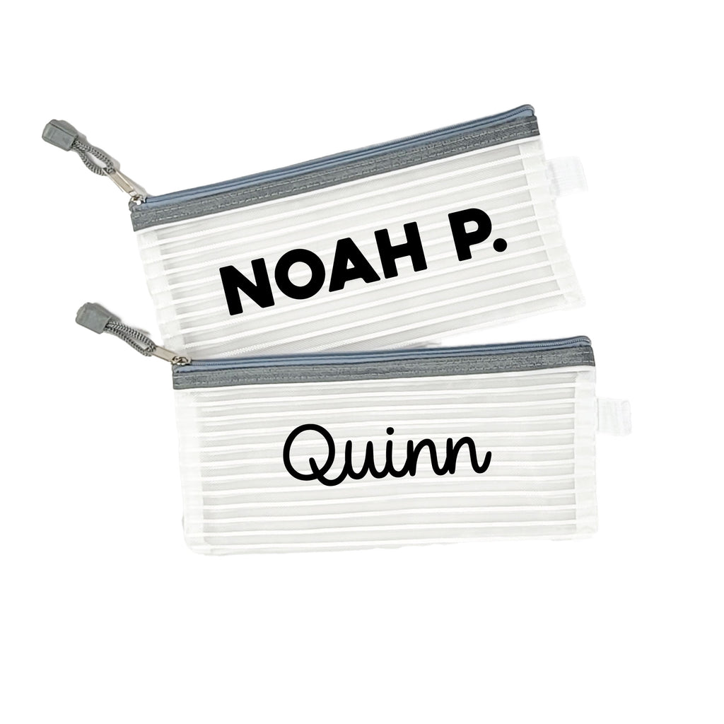 Two grey InchBug personalized zipper pouches with the names 'NOAH P.' and 'Quinn' printed on them.