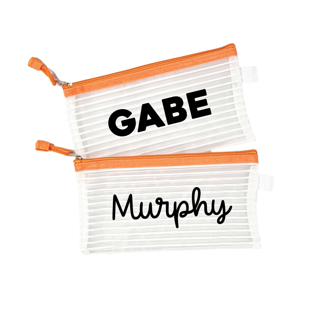 Two orange InchBug personalized zipper pouches with a striped pattern, one labeled 'GABE' and the other with 'Murphy' in bold black lettering on a white background.